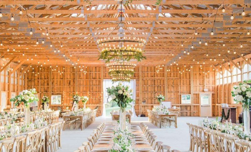rustic barn reception hall with greenery and string lights