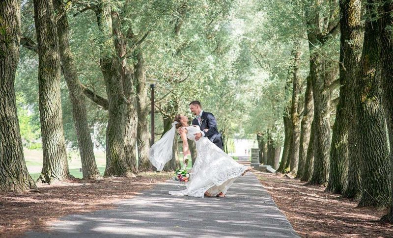 Bride and groom on a sunny tree-lined road