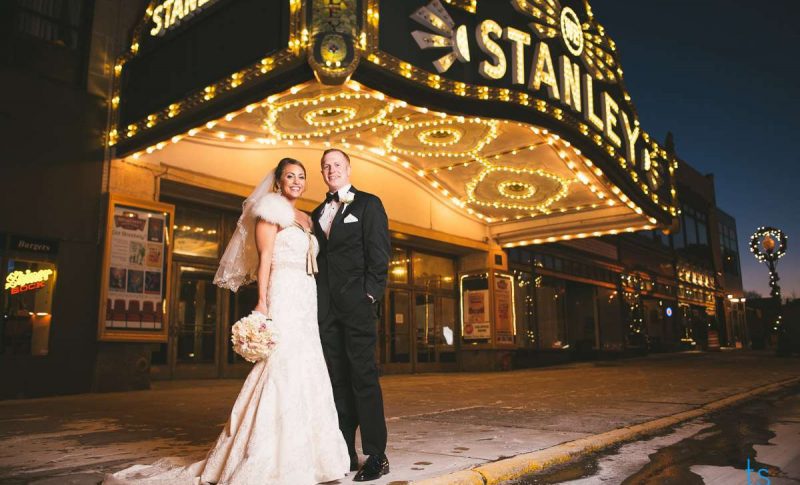 Bride and groom stand at entrance to theater at night
