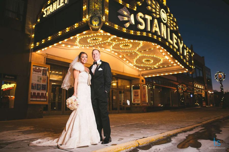 Bride and groom stand at entrance to theater at night